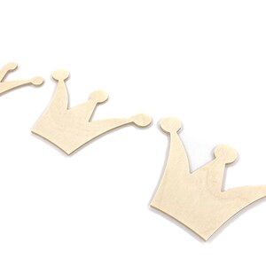 May include: Three unfinished wooden crown shapes, arranged in a row, with the largest crown on the right and the smallest crown on the left.