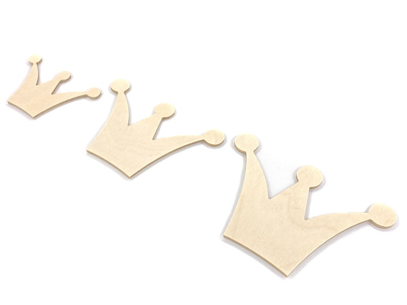 May include: Three unfinished wooden crown shapes, arranged in a row, with the largest crown on the right and the smallest crown on the left.