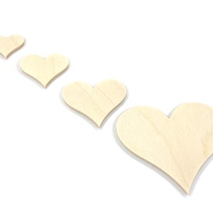May include: Four wooden hearts of varying sizes, arranged in a row from smallest to largest, on a white background.