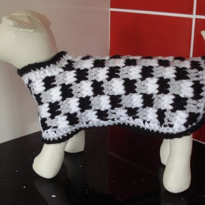 May include: A black and white checkered crocheted dog sweater. The sweater is made with a soft yarn and has a comfortable fit.