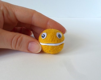 May include: A small, yellow felt ball with a white felt mouth and two black googly eyes.