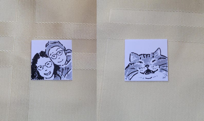 May include: Two small square drawings. One shows two people smiling, wearing glasses, and drawn in black and white. The other shows a smiling cat, also in black and white.