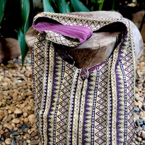 Op de afbeelding: Een tote bag met een geometrisch patroon in paars en goud. De tas is gemaakt van stof en heeft een lange band.