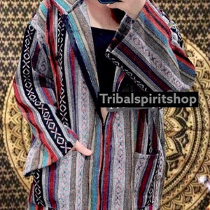 K&ouml;nnte beinhalten: Kapuzenjacke mit farbenfrohem Streifenmuster in Rot, Blau, Grau und Schwarz. Die Jacke hat einen Frontrei&szlig;verschluss und zwei Taschen. Der Text "Tribalspiritshop" ist sichtbar.