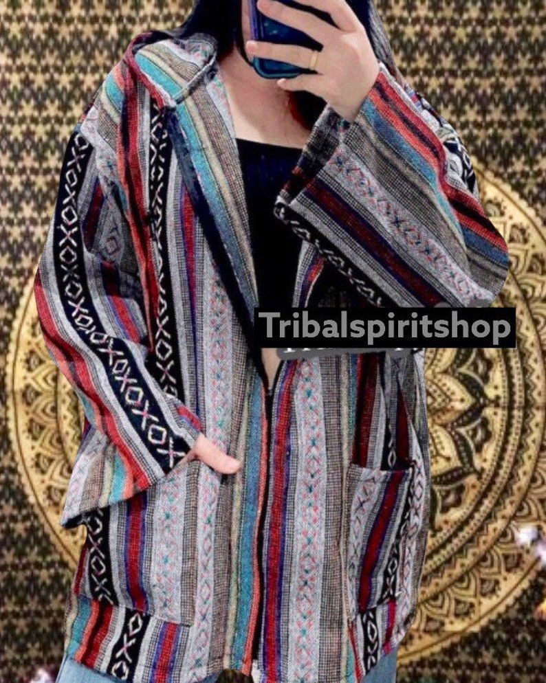 K&ouml;nnte beinhalten: Kapuzenjacke mit farbenfrohem Streifenmuster in Rot, Blau, Grau und Schwarz. Die Jacke hat einen Frontrei&szlig;verschluss und zwei Taschen. Der Text "Tribalspiritshop" ist sichtbar.