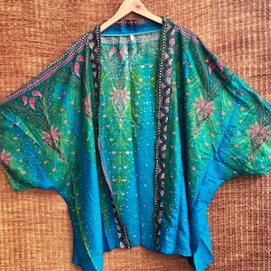 May include: A blue and green silk kimono with a peacock feather design. The kimono has a wide, flowing silhouette and is decorated with sequins and beads.