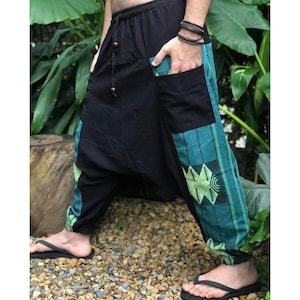May include: Black and green patterned pants with a loose fit and a drawstring waist. The pants have a large pocket on the left side and a smaller pocket on the right side.