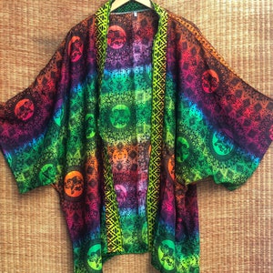 Peut inclure: Un kimono tie-dye arc-en-ciel avec un motif mandala noir et vert repr&eacute;sentant des &eacute;l&eacute;phants. Le kimono est orn&eacute; d'une bordure verte et d'une bordure noire et jaune sur le devant.
