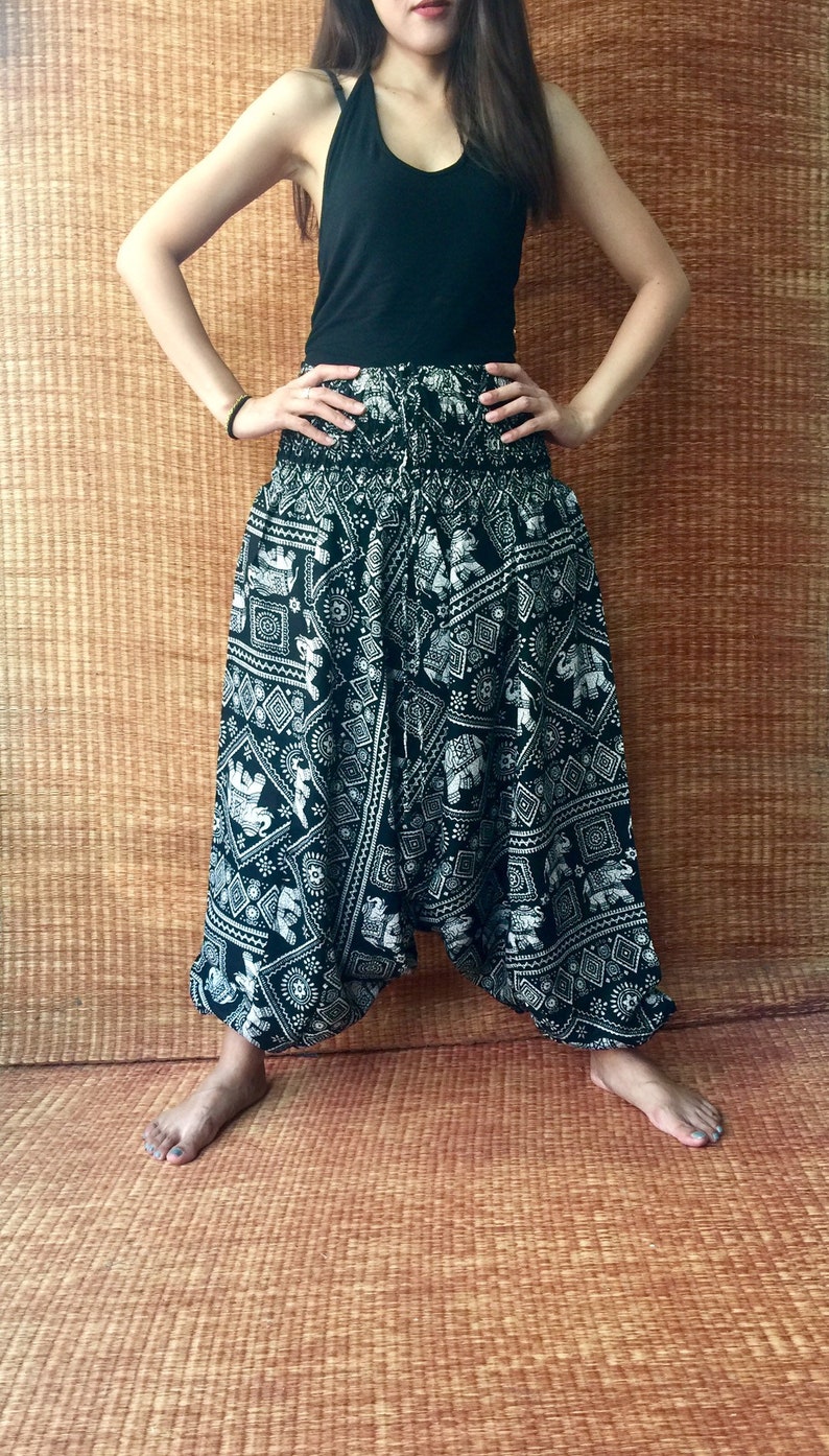 May include: Black and white printed pants with an elephant design. The pants are loose fitting and have a wide leg.