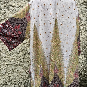 May include: White kimono with a peacock feather design in shades of green, yellow, and red. The kimono has a paisley pattern on the sleeves and hem.