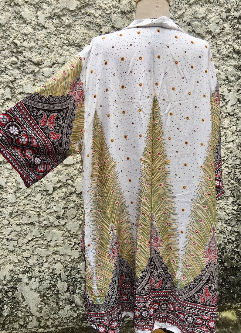 May include: White kimono with a peacock feather design in shades of green, yellow, and red. The kimono has a paisley pattern on the sleeves and hem.