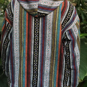 K&ouml;nnte beinhalten: Eine Kapuzenjacke mit einem farbenfrohen Streifenmuster. Die Jacke hat vertikale Streifen in verschiedenen Farben, darunter Rot, Blau, Gelb und Schwarz. Die Kapuze und die Schultern haben ein gemustertes Design. Die Jacke ist aus einem gewebten Stoff gefertigt.