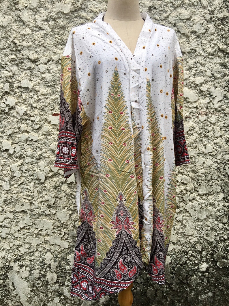 May include: White long-sleeved tunic with a paisley print in shades of green, red, and black. The tunic has a V-neck and a button closure.
