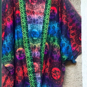 Peut inclure: Un kimono color&eacute; avec un motif ombr&eacute; arc-en-ciel et un imprim&eacute; d'&eacute;l&eacute;phant noir. Le kimono a une bordure verte et noire.