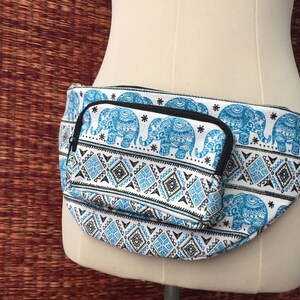 May include: White fanny pack with a blue and black elephant print. The pack has a small zippered pocket on the front.