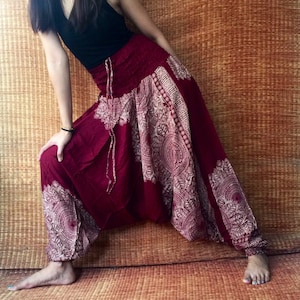 May include: Burgundy harem pants with a white floral pattern. The pants have a drawstring waist and are made of a soft, flowing fabric.