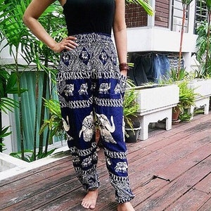 Puede incluir: Una mujer con un top negro de tirantes y pantalones azules y blancos con estampado de elefantes. Los pantalones tienen pierna ancha y un corte holgado.