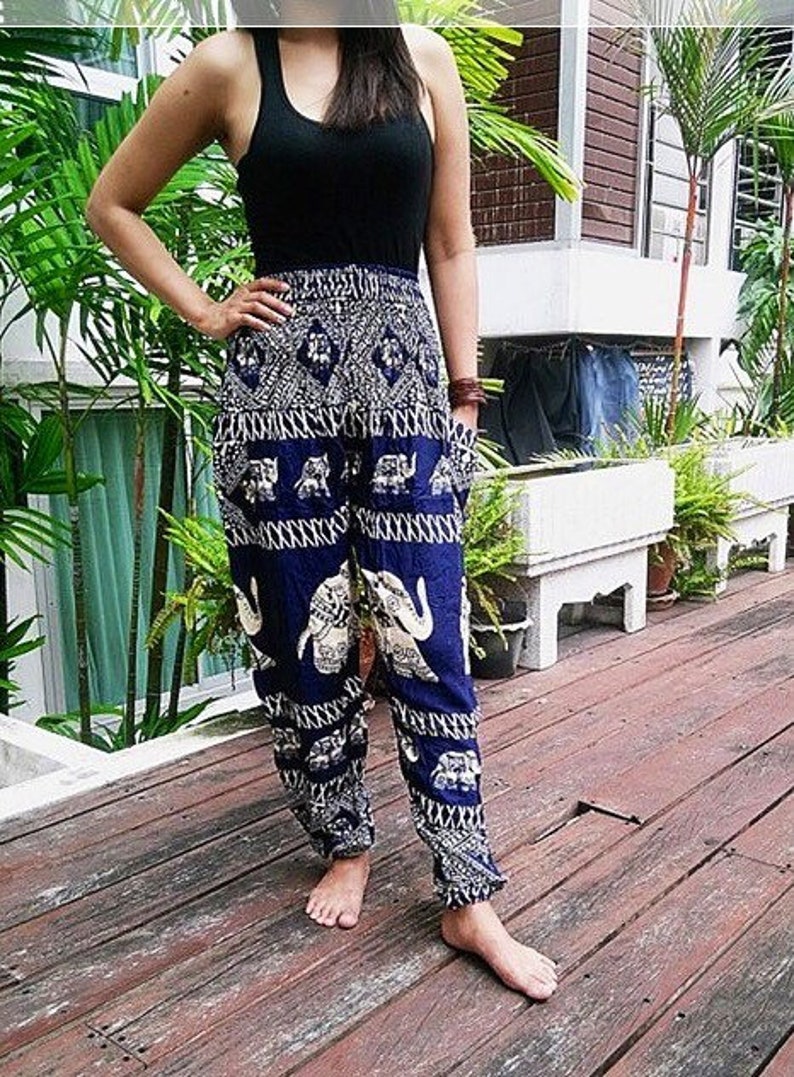 Puede incluir: Una mujer con un top negro de tirantes y pantalones azules y blancos con estampado de elefantes. Los pantalones tienen pierna ancha y un corte holgado.