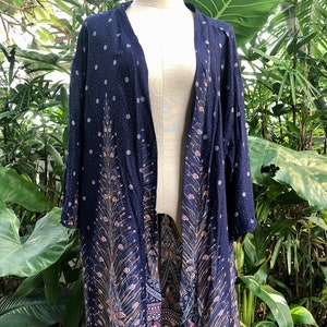 May include: A navy blue kimono with a peacock feather design and white polka dots. The kimono has a long, flowing silhouette and is made of a lightweight fabric.