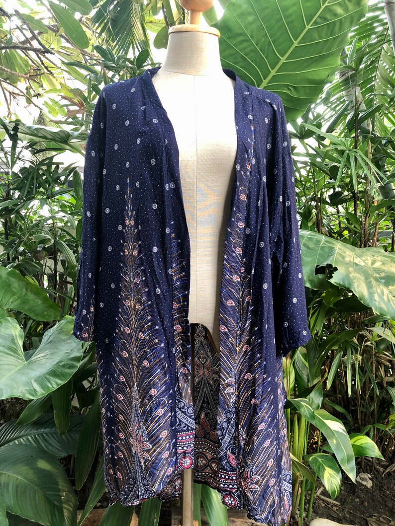 May include: A navy blue kimono with a peacock feather design and white polka dots. The kimono has a long, flowing silhouette and is made of a lightweight fabric.