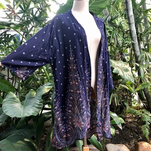 May include: A navy blue kimono with a peacock feather design. The kimono has a white polka dot pattern and a gold and pink trim.