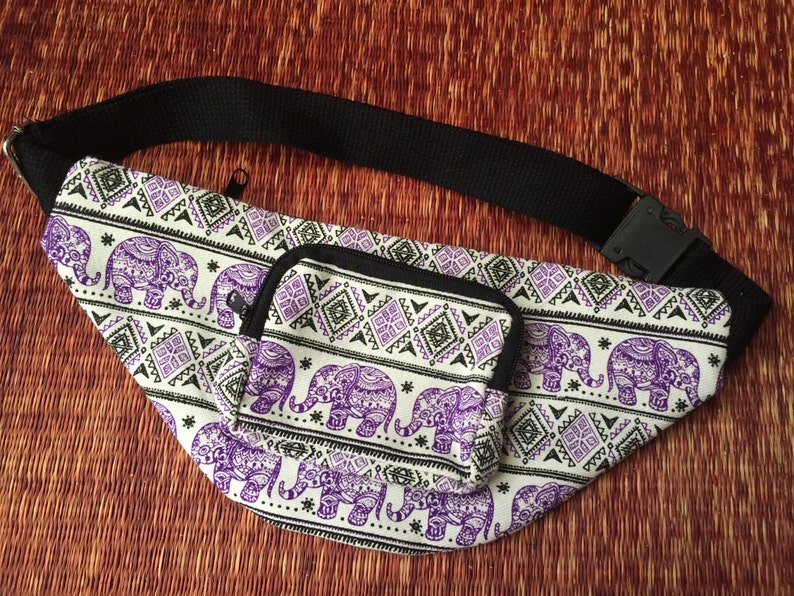 May include: A white fanny pack with a purple and black elephant pattern. The fanny pack has a small zipped pocket on the front.
