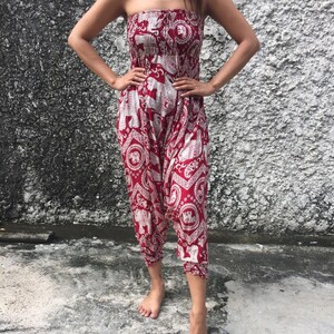 K&ouml;nnte beinhalten: Roter, tr&auml;gerloser Jumpsuit mit einem wei&szlig;en Elefantenmuster. Der Jumpsuit hat eine geraffte Taille und weite Beine.