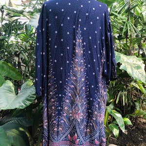 May include: A navy blue long-sleeved shirt with a peacock design. The shirt has a white polka dot pattern and a paisley border.