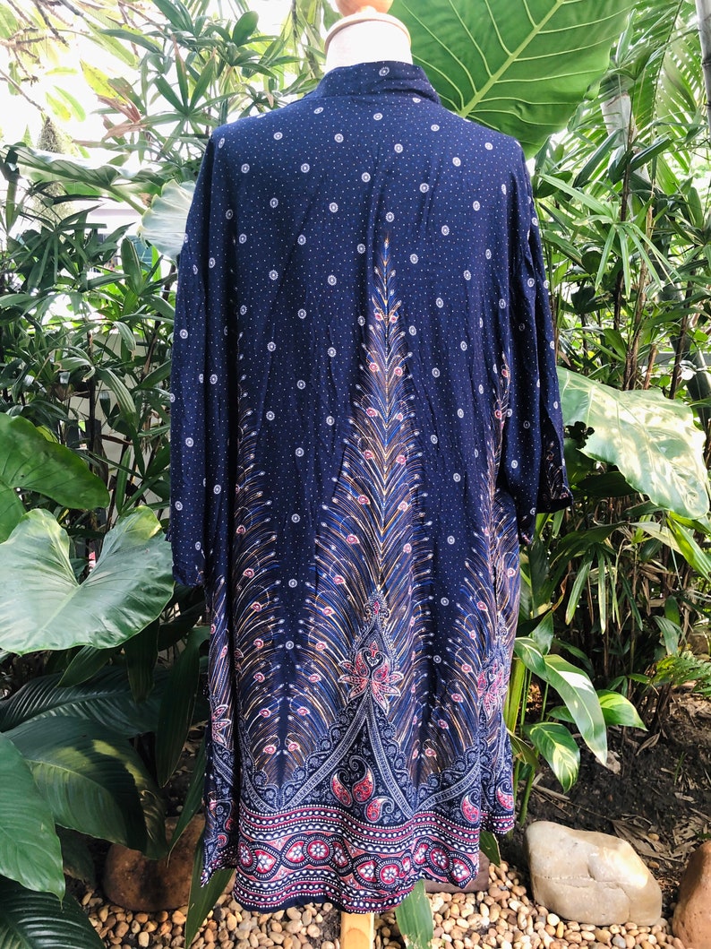 May include: A navy blue long-sleeved shirt with a peacock design. The shirt has a white polka dot pattern and a paisley border.