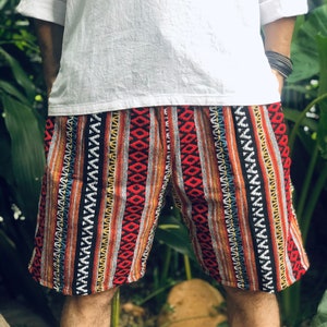 May include: Red, black, white and blue patterned shorts with a geometric design. The shorts are made of a woven fabric.