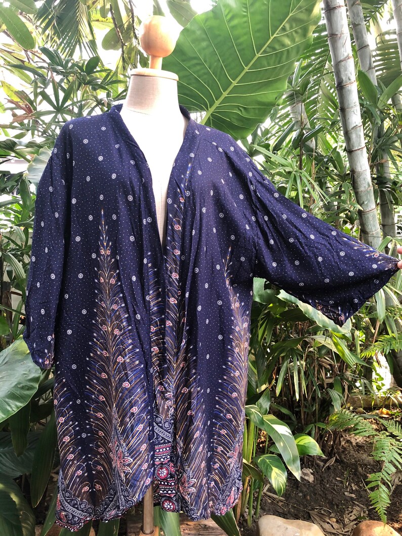 May include: A navy blue kimono with a peacock feather design and white polka dots. The kimono has a long, flowing silhouette and is made of a lightweight fabric.