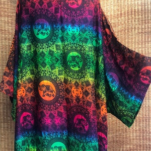 Peut inclure: Un kimono en ombr&eacute; arc-en-ciel avec un motif de mandala noir et des silhouettes d'&eacute;l&eacute;phants. Le kimono a une coupe ample et est fait d'un tissu l&eacute;ger.