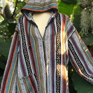 K&ouml;nnte beinhalten: Kapuzenjacke mit farbenfrohem Streifenmuster. Die Jacke hat einen durchgehenden Rei&szlig;verschluss, zwei Vordertaschen und eine Kapuze mit Kordelzug. Die Streifen sind rot, blau, gelb und schwarz. Die Jacke wird auf einer Schaufensterpuppe pr&auml;sentiert.