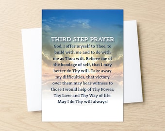 May include: A white greeting card with the text "THIRD STEP PRAYER" against a backdrop of a blue sky with clouds. The card is inside a white envelope, resting on a light wood surface.