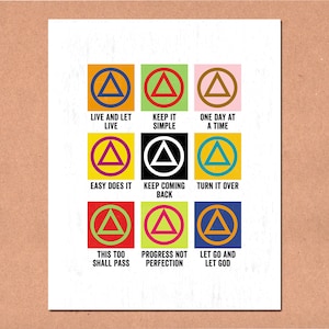 Puede incluir: Una impresión blanca con nueve cuadrados coloridos, cada uno con un símbolo de triángulo y una frase. Las frases incluyen "Live and Let Live", "Keep it Simple" y "One Day at a Time". La impresión está sobre un fondo marrón.