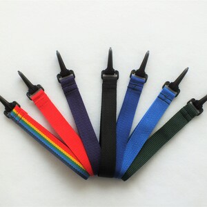 Peut inclure: Sept lanyards colorés avec des clips en plastique noir. Les lanyards sont arc-en-ciel, rouge, violet, noir, bleu, vert et bleu foncé.