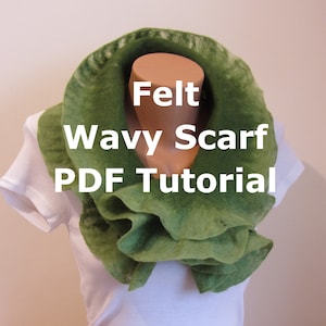 May include: A green felt scarf with a wavy design. The scarf is displayed on a mannequin wearing a white shirt. The text "Felt Wavy Scarf PDF Tutorial" is written on the scarf.
