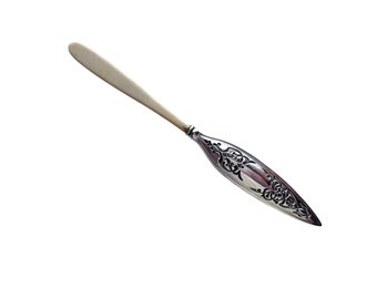 May include: A silver butter knife with a white bone handle and an ornate design on the blade.