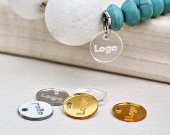 Può includere: Un braccialetto di perline turchesi e bianche con un ciondolo d'argento che dice "Logo". Il ciondolo è appeso al braccialetto. Ci sono anche diversi ciondoli trasparenti e dorati con la parola "Logo" su di essi.