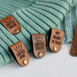 May include: Four brown leather tags with text and a crown design. The tags read "Coffee Queen", "Coffee King", "Not Ready To Talk", and "Not Ready To Talk".