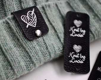 Custom black and silver tags for handmade items, size 2.5x1 inches with fasteners for beanies