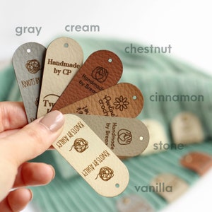 May include: A fan of eight leather labels in various shades of brown, cream, and gray. Each label has a different design and text, including "Handmade by CP", "Cauline Crochet by Brean", and "Knots by Ashley".