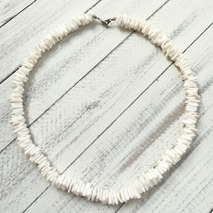 May include: A white shell necklace with a silver clasp. The necklace is made of flat, rectangular pieces of shell.