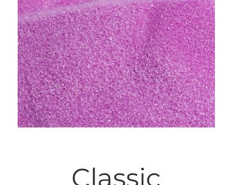 May include: Close-up of mauve colored sand. The sand is fine and has a slightly shimmery texture.