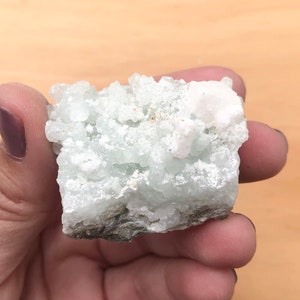 May include: A cluster of white and green crystals with a rough, natural texture. The crystals are clustered together in a dense formation, creating a unique and interesting piece.