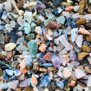 May include: A collection of small, colorful, and textured stones. The stones are a mix of different shapes and sizes, and they are arranged in a random pattern. The stones are a variety of colors, including white, black, brown, green, blue, and purple.