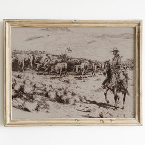 May include: A black and white drawing of a cowboy on horseback leading a herd of cattle across a grassy plain. The drawing is framed in a light wood frame.