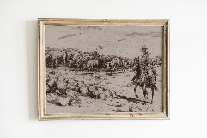 May include: A black and white drawing of a cowboy on horseback leading a herd of cattle across a grassy plain. The drawing is framed in a light wood frame.