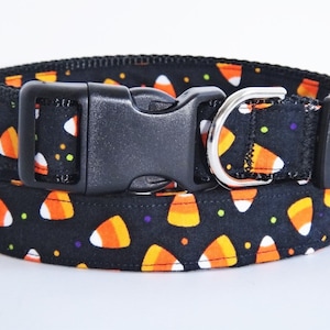 May include: Black dog collar with a candy corn pattern. The collar has a black buckle and a silver D-ring.