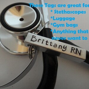 May include: A silver metal tag with the text "Brittany RN" engraved on it. The tag is attached to a stethoscope.